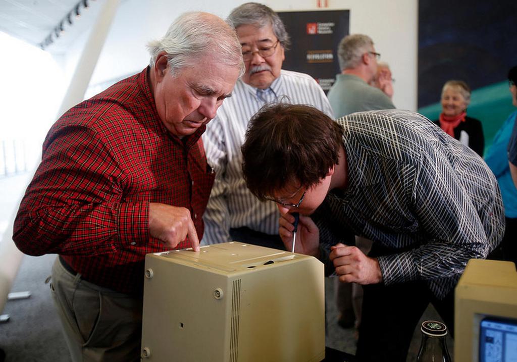 Early apple employee Jerry Manock, left, and Adam Goolevitch, right, from Canada, take apart a
