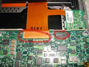 Remove the two Torx T8 screws as shown in red. Locate the DVD drive and two orange cables connected to the motherboard.