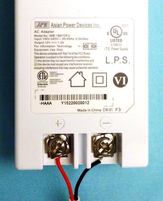11. At the location of the power source, connect the power cable to the power adapter: Screw the red wire onto the positive (+) terminal of the power adapter, on the left side.