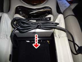 Place the audio cable end on the front seat and replace storage bin. 11.