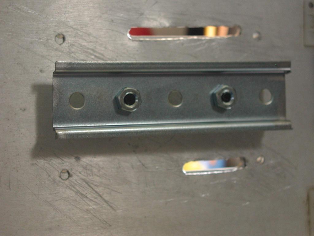 Secure the din rail as shown below. Use all 6 ¼-20 nuts, by using two to secure it to the cabinet and the other 4 to stand off the din rail so the board is clear of the screws.