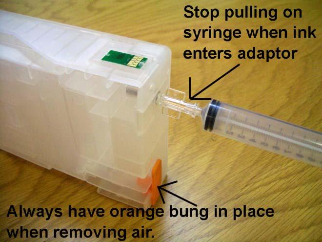 To remove this trapped air, take the priming syringe with end adaptor fitted and gently insert the syringe through the rubber seal in the ink exit valve at the front of a cartridge, as in this