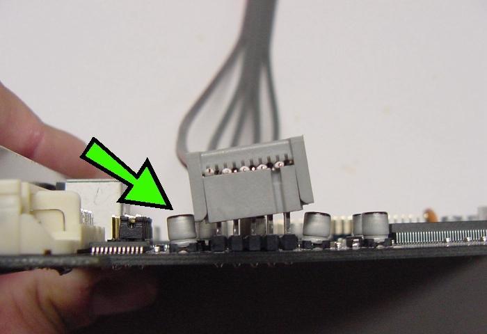 First, gently press one side of the cable connector onto the pins, to gently nudge the metal cylinder outwards slightly (as indicated by green