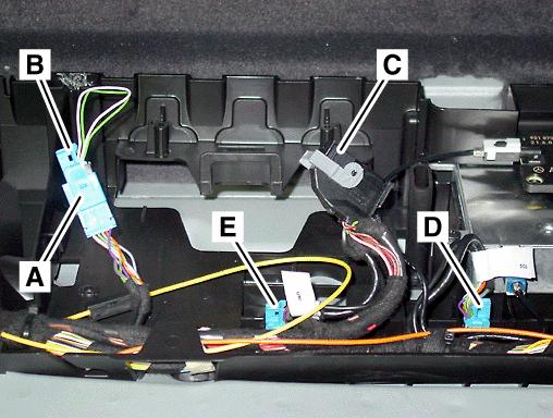 In the left side compartment of the carrier plate, find the: Tele Aid microphone connector (A, Figure 5) and connected jumper (B, Figure 5) with green and white looped wires MHI