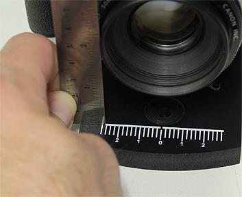 This is accomplished by holding the ruler at some arbitrary same place on each side of the lens and letting the ruler