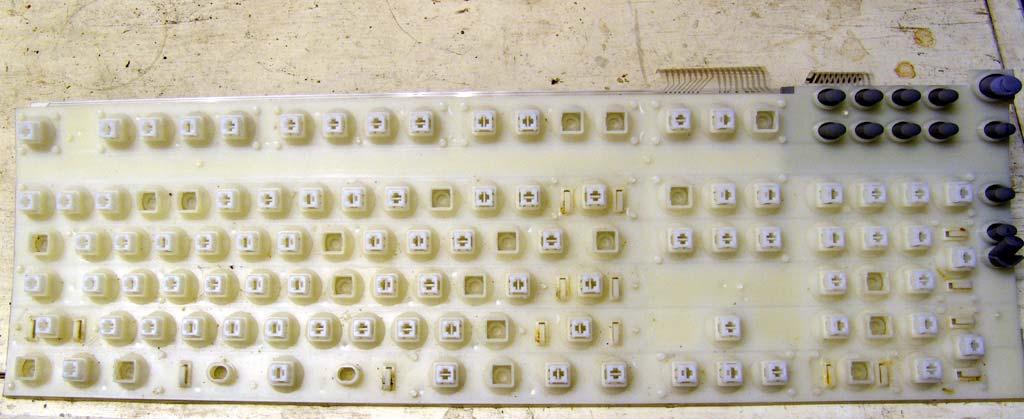 The outer shell removed, along with all of the keycaps. Most of the lint and dirt has been blown free or wiped free. At the top right, we see the ribbon connectors that connect to the circuit board.