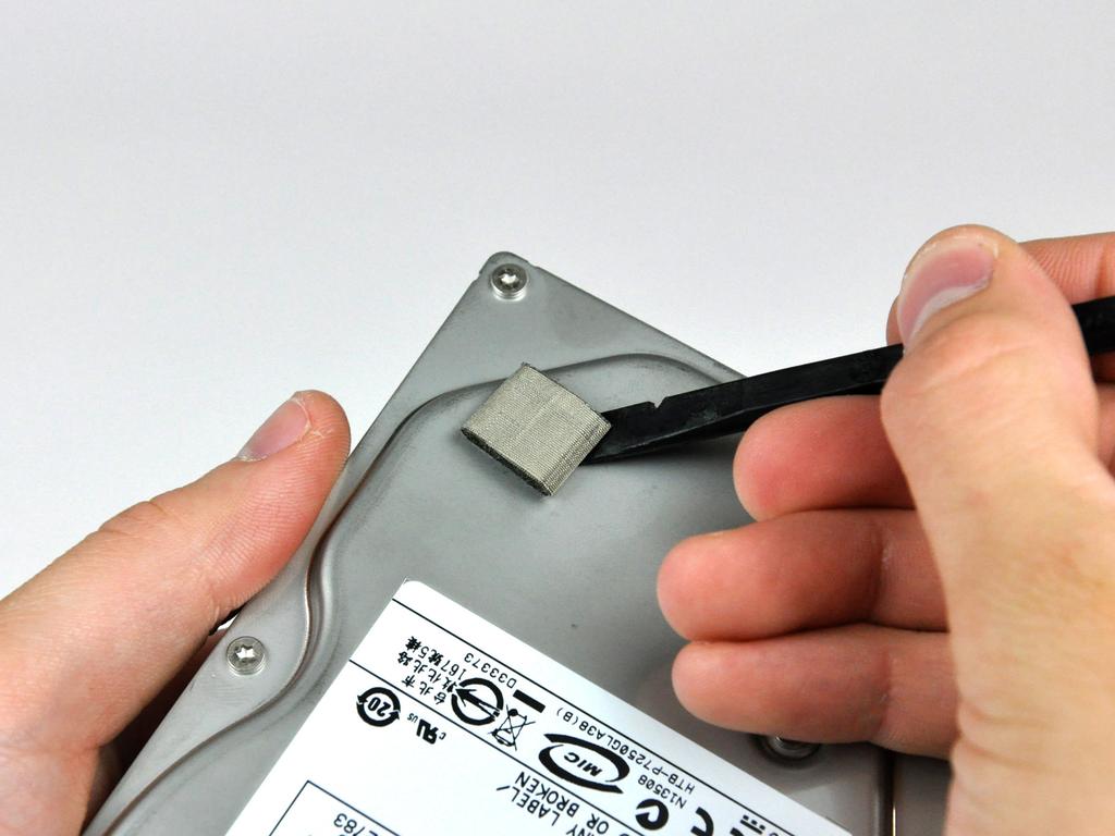 Step 24 Use the flat end of a spudger to remove the piece of EMI foam from the underside of your hard drive.