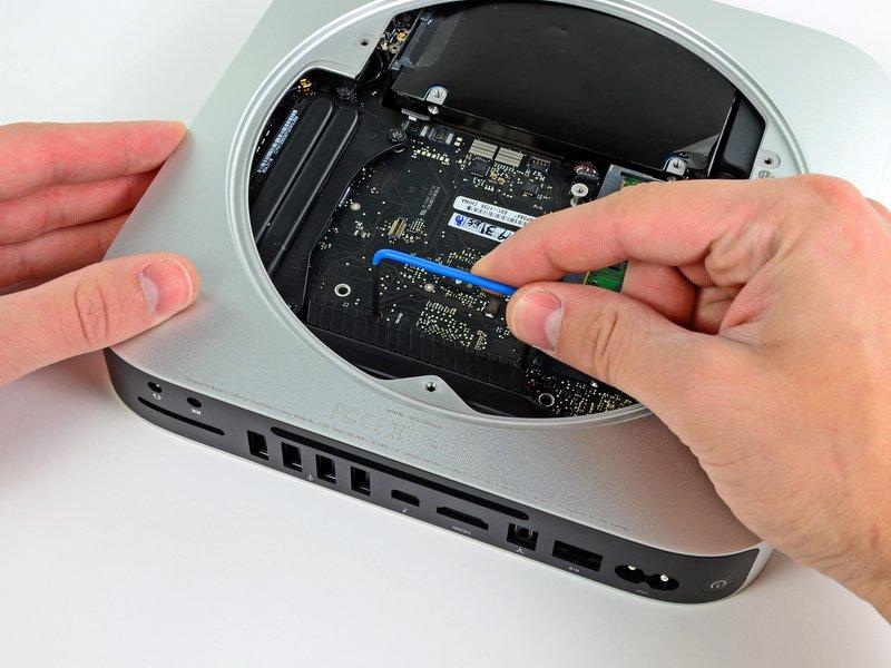 Insert the Mac mini Logic Board Removal Tool into the two holes highlighted in red. Be sure it makes contact with the top side of outer case below the logic board before proceeding.