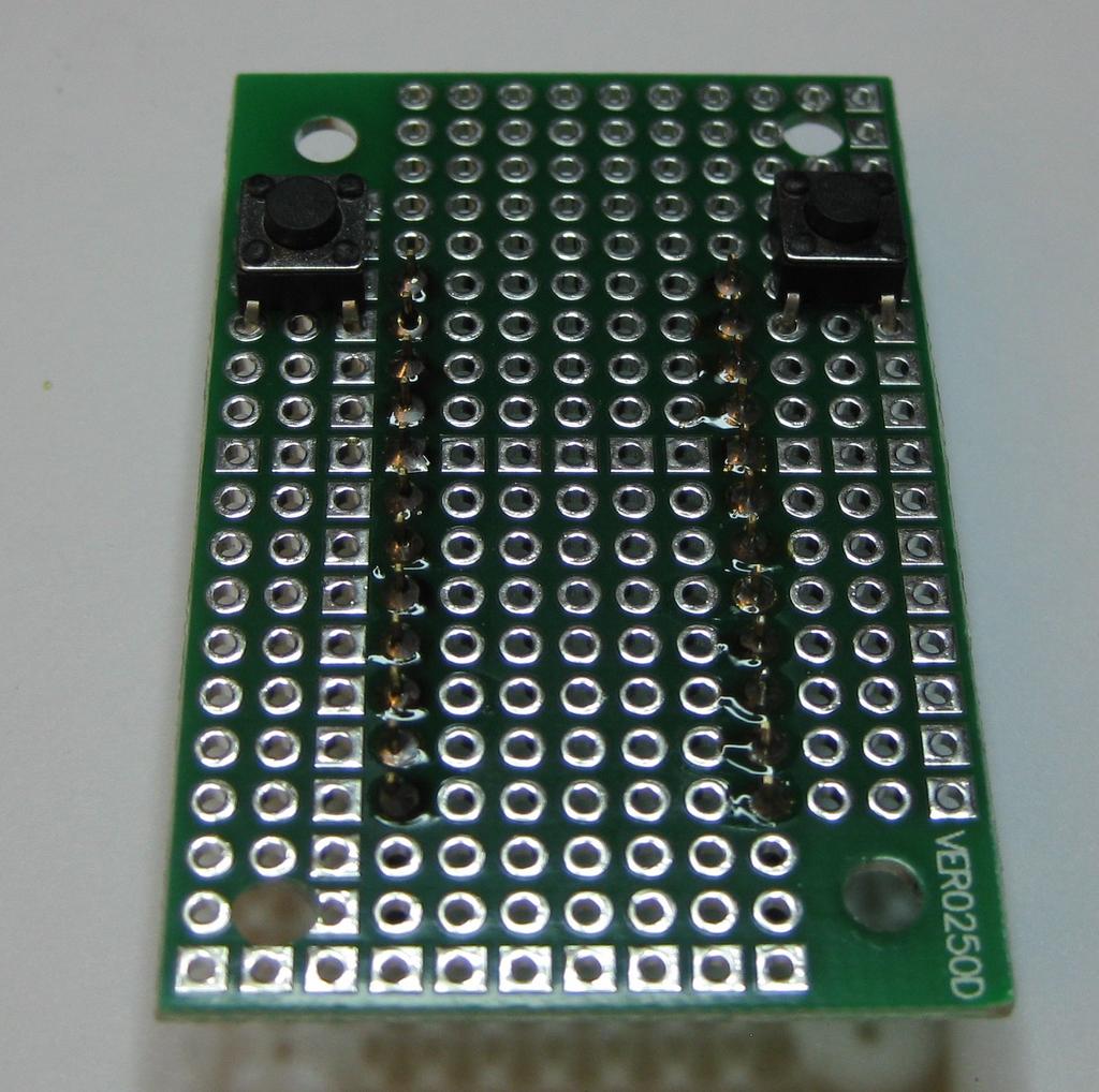 Solder the two Tactile Push Buttons to the backside of the protoboard as shown below.