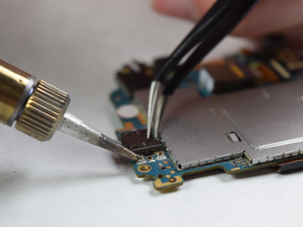 Step 27 Using a soldering iron set at 400 degrees Celsius (752 degrees Fahrenheit), heat the solder joints lateral to the USB port. Use a pair of tweezers to lift the port from the board.