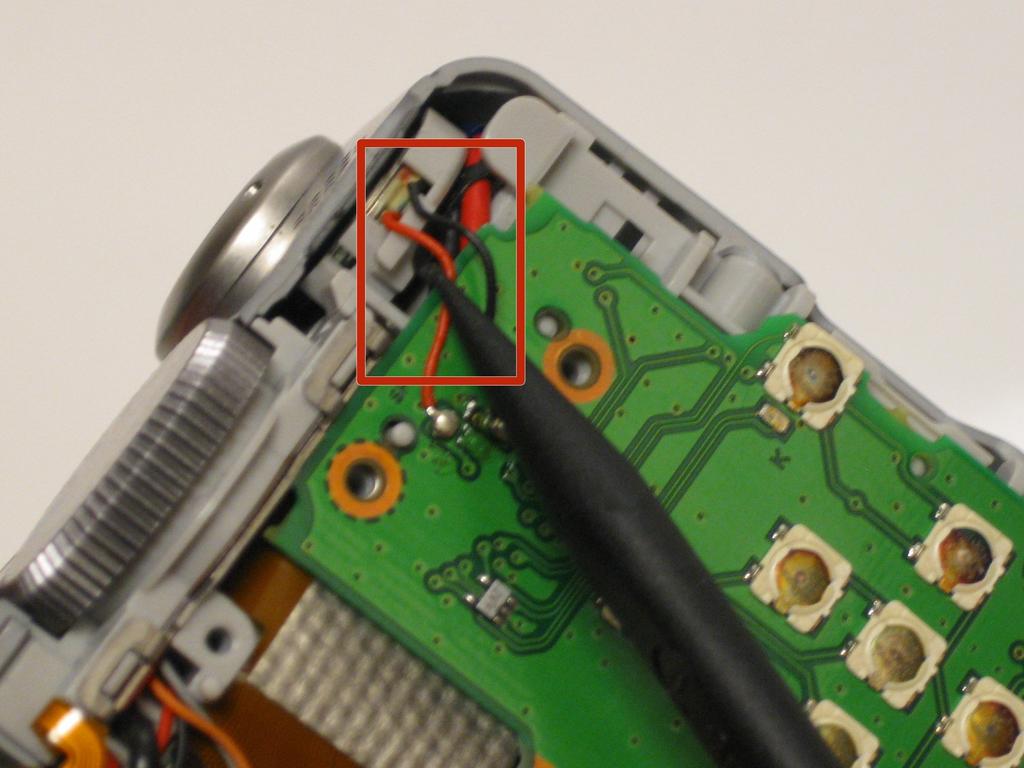 Step 8 Use the spudger to unclip both wires from underneath the shutter button and