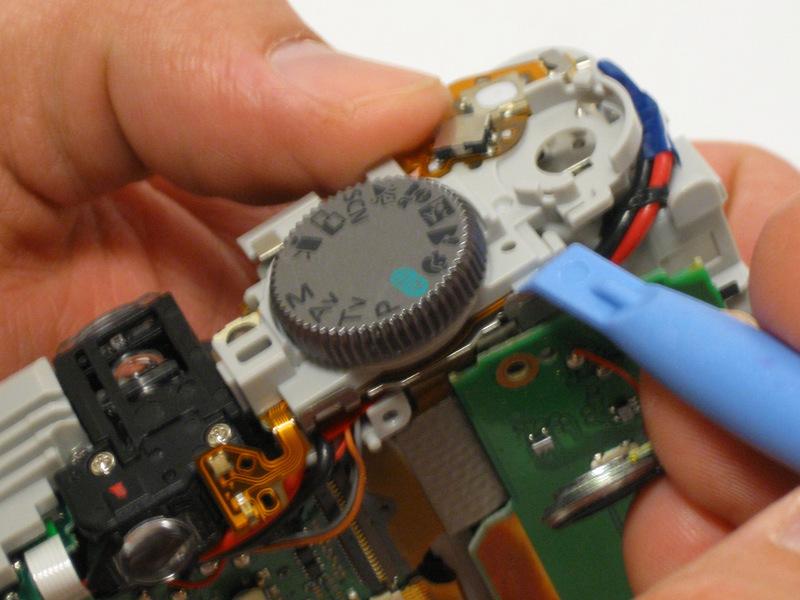Step 10 Use the plastic opening tool to begin separating the user button circuit board from the