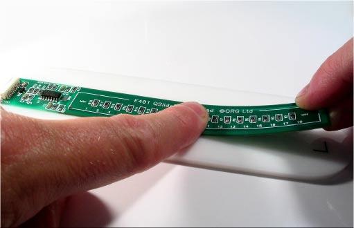 Bend the PCB slightly as shown while smoothing it to remove any air bubbles.