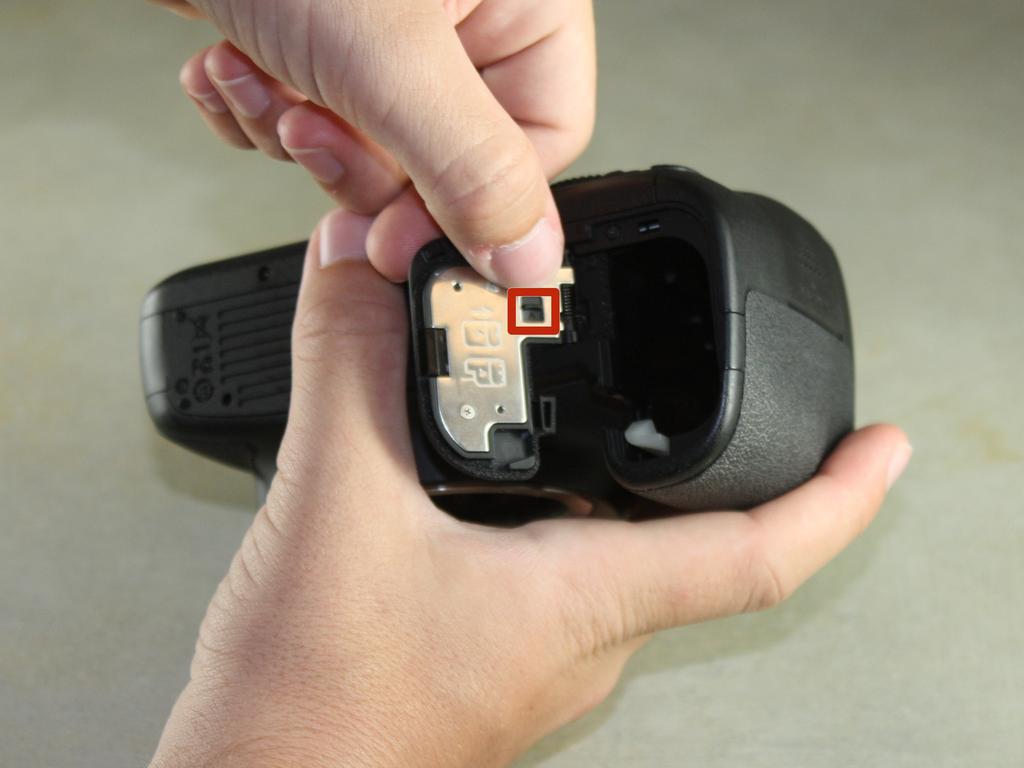 Use your thumb to slide the small black tab on the inside of the battery door