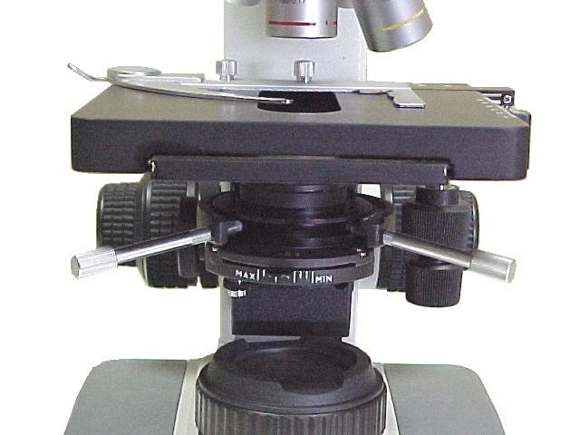 Specimen holder mechanism (6): Turn the coarse focus knob (16) until the stage (8) reaches its lowest position. Unscrew the two locking screws (Fig. 1) of the specimen holder mechanism.
