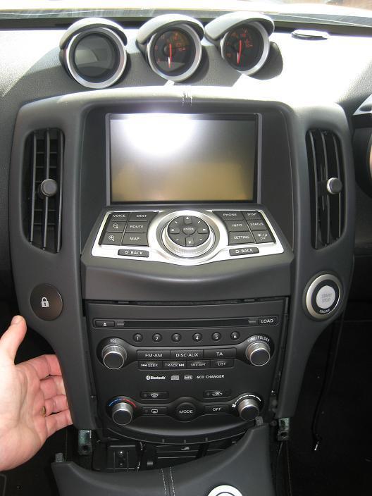 The centre console will still be attached to the top of the dash board above the Sat Nav screen by 3 clips. Gently lift and pull the console to unclip it.