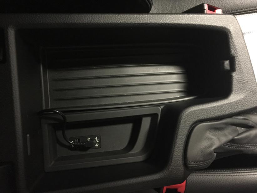This is usually located in the centre armrest and can be routed through the centre console and under the rubber