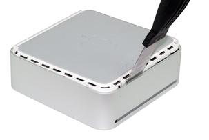 Insert a thin-blade putty knife between the aluminum housing and the white plastic inner chassis of the Mac mini at one corner, as shown at left.